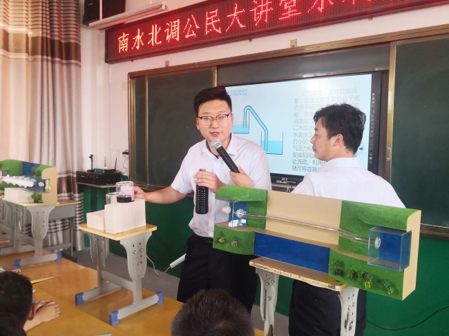 为学生们现场展示科学小实验“虹吸原理”