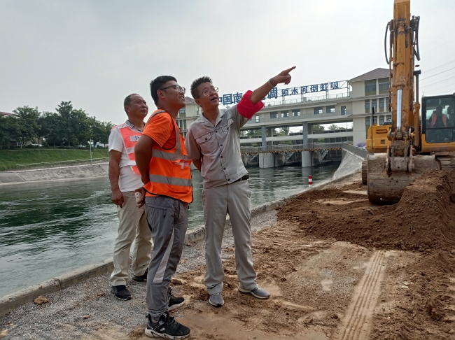 祁建华在现场与工人一起讨论施工工序