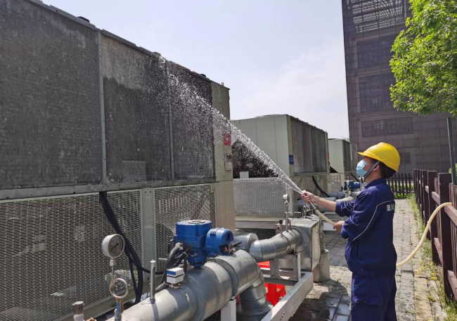 运维人员正在清理附着在变频器冷水机组上的杨柳絮