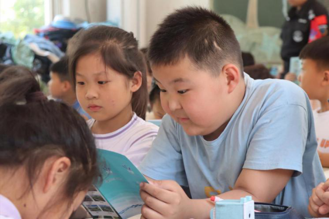 长葛市添才学校的学生围坐在一起看宣传画册